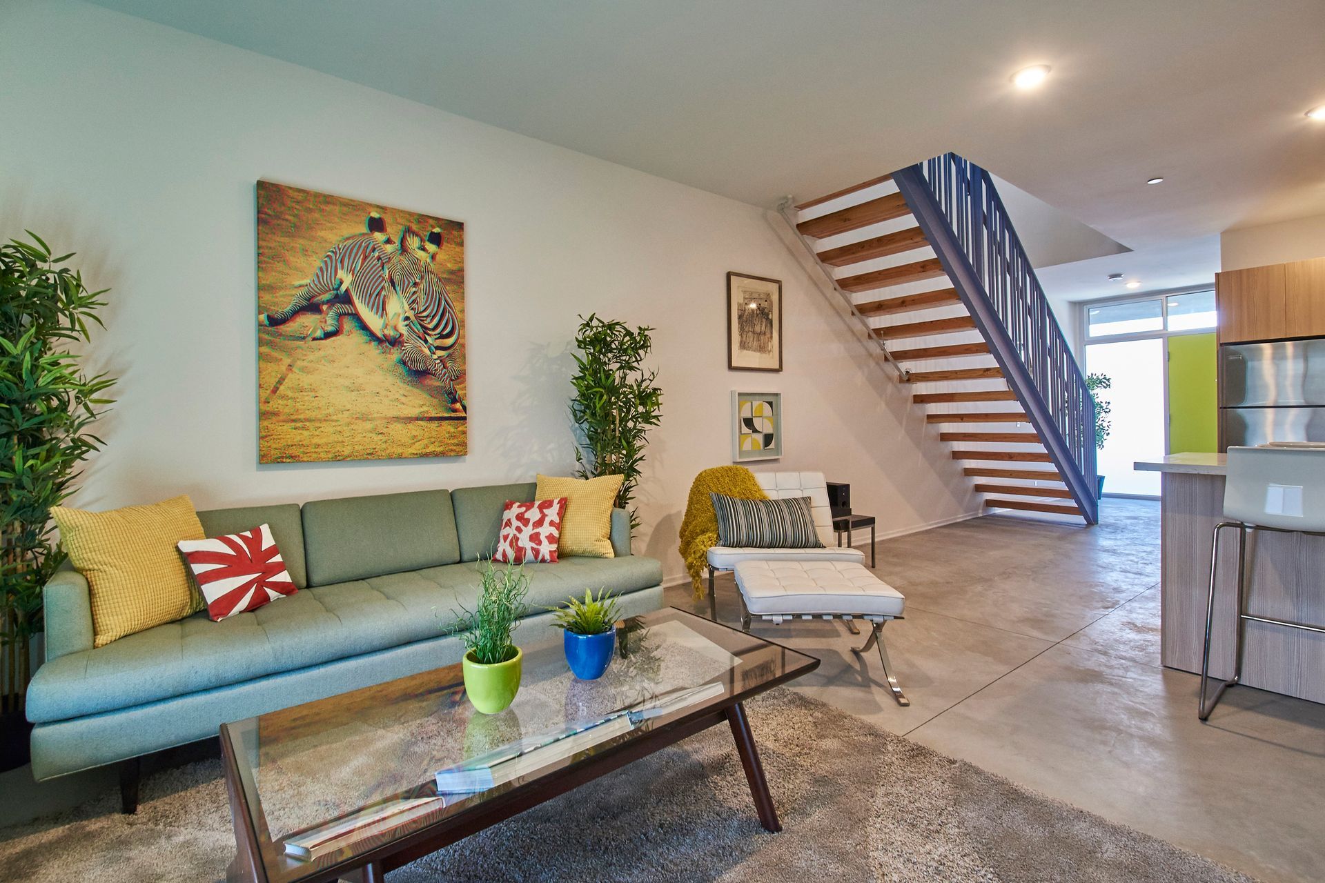 A living room with a couch , coffee table , chair and stairs.
