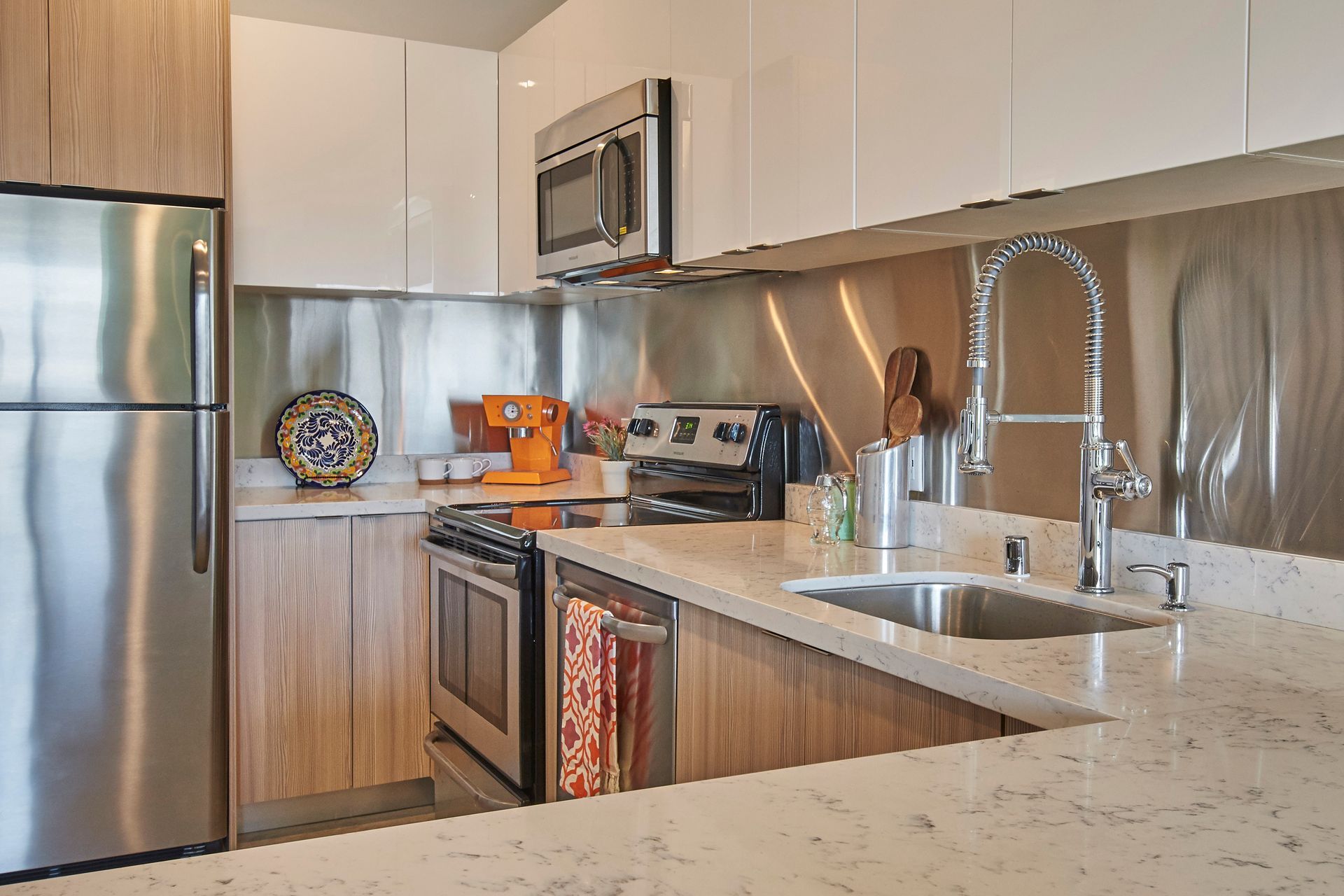A kitchen with a sink , refrigerator , stove and microwave.