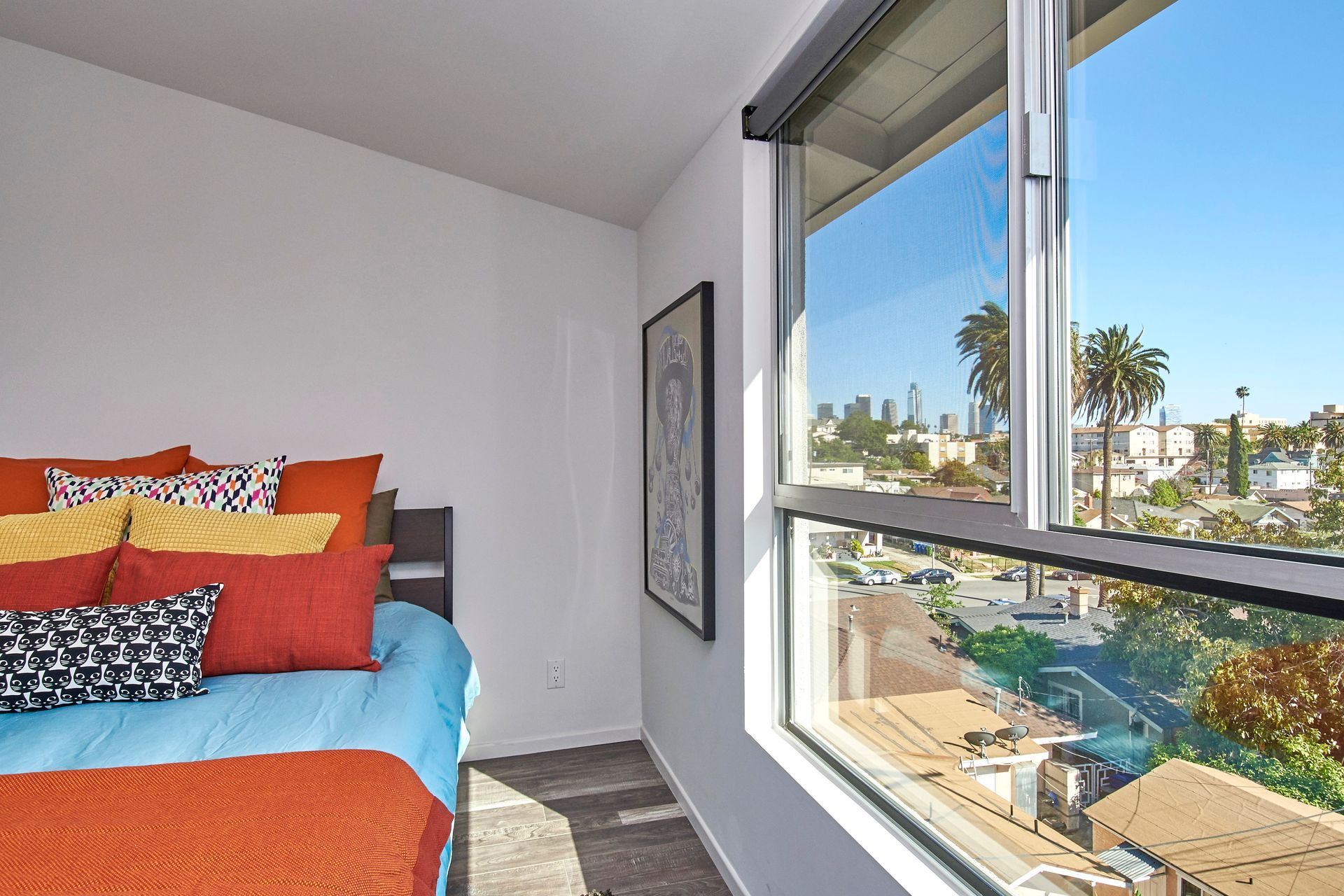 A bedroom with a bed and a window with a view of a city.