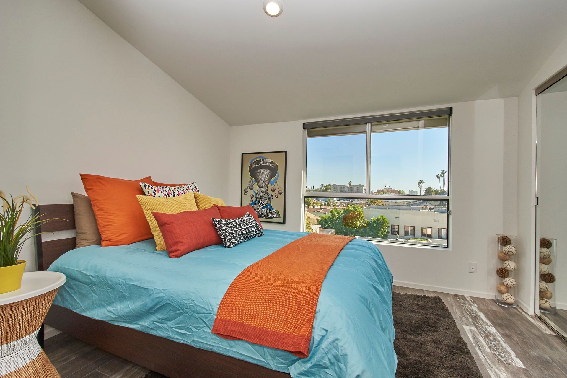 A bedroom with a blue bed and orange pillows