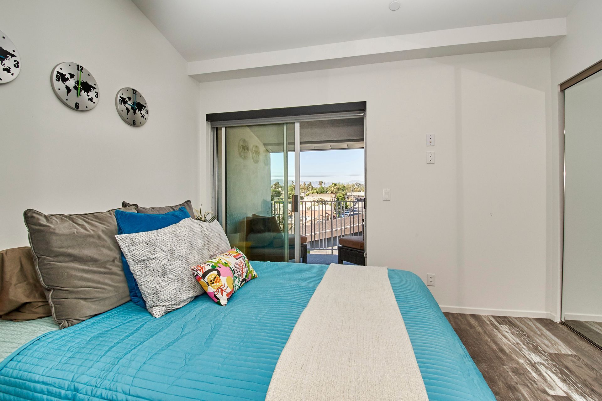 A bedroom with a blue bed and a sliding glass door leading to a balcony.