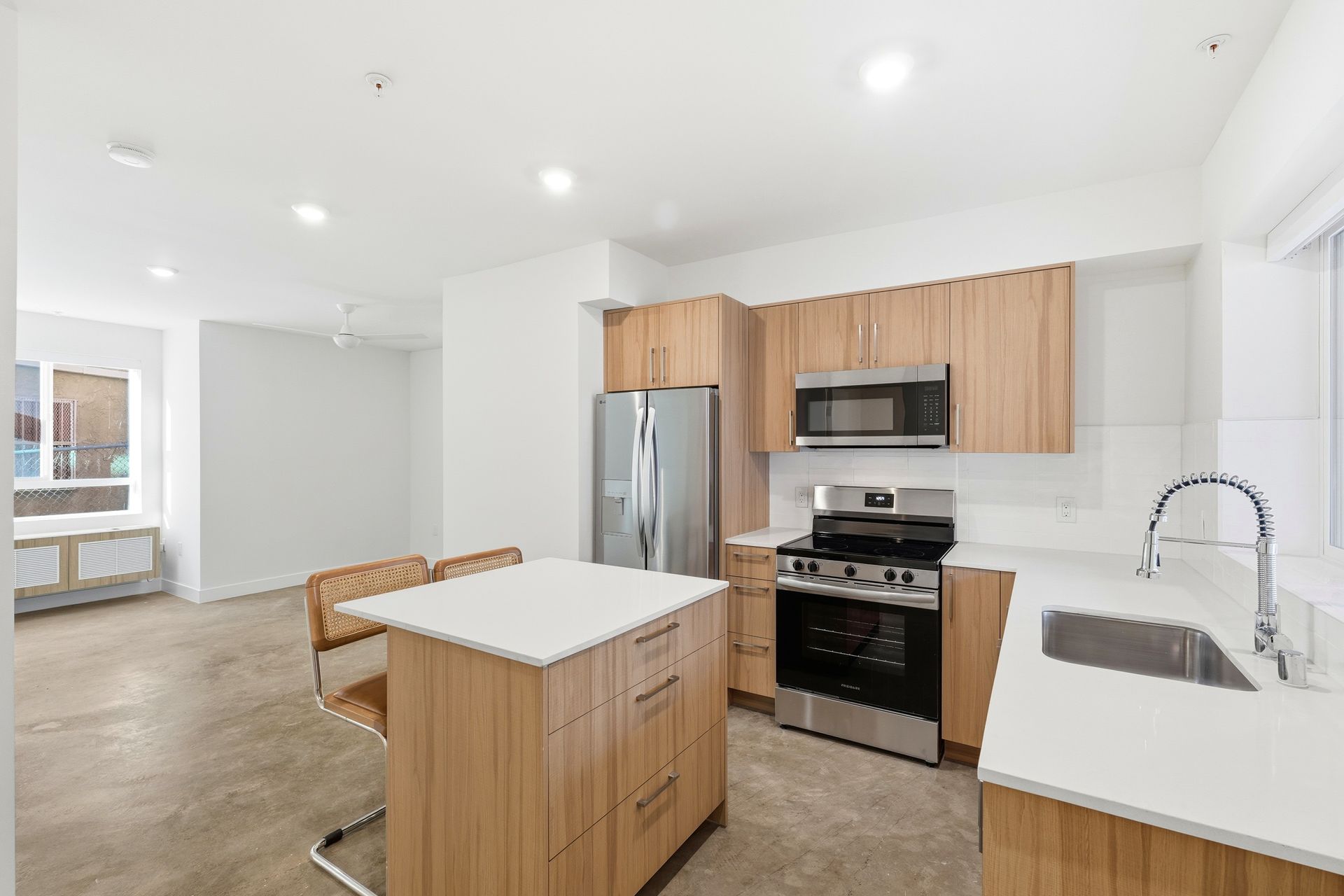 Modern kitchen with wooden cabinets, stainless steel appliances, and a white countertop island.