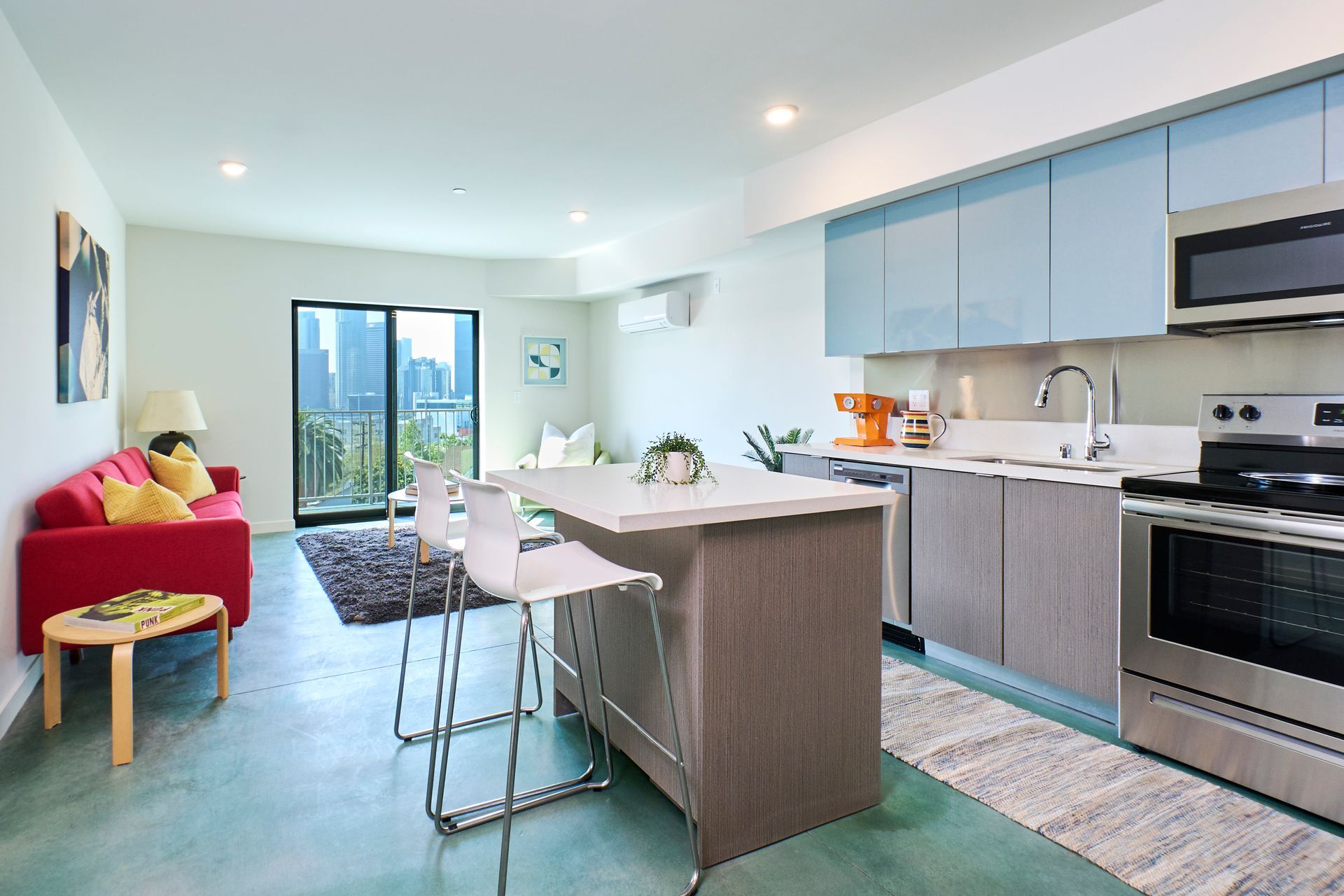 A living room with a red couch and a kitchen with stainless steel appliances