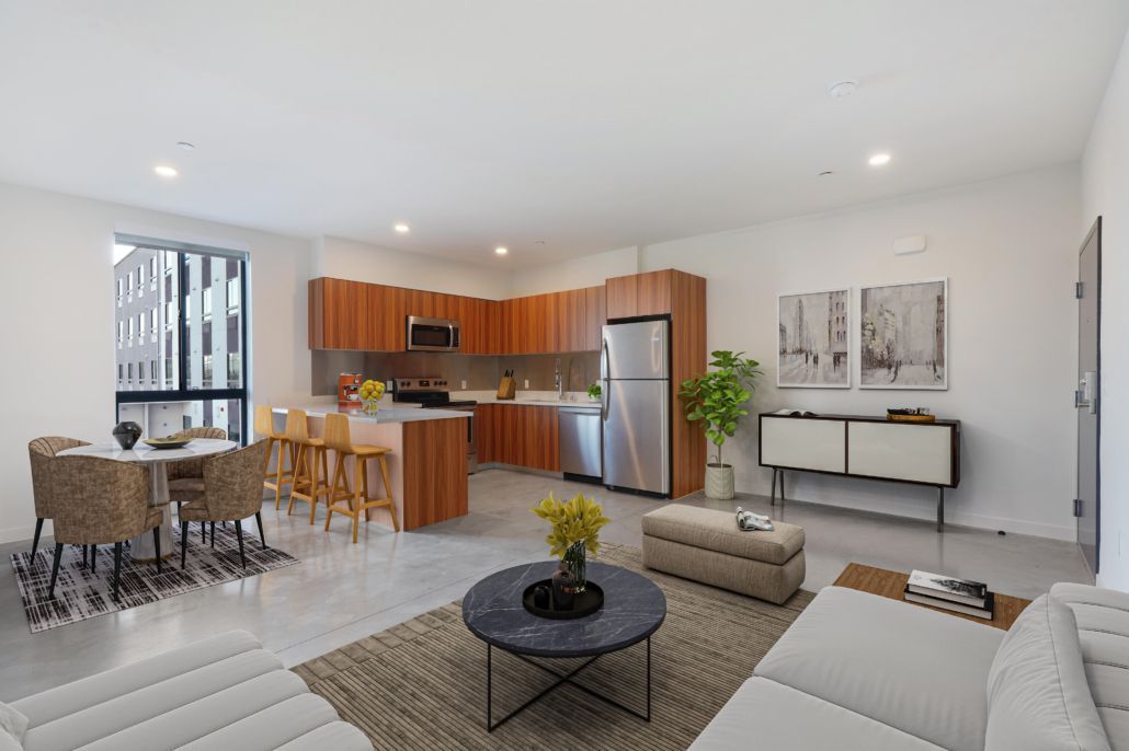 A living room with a couch , table , chairs and a kitchen.