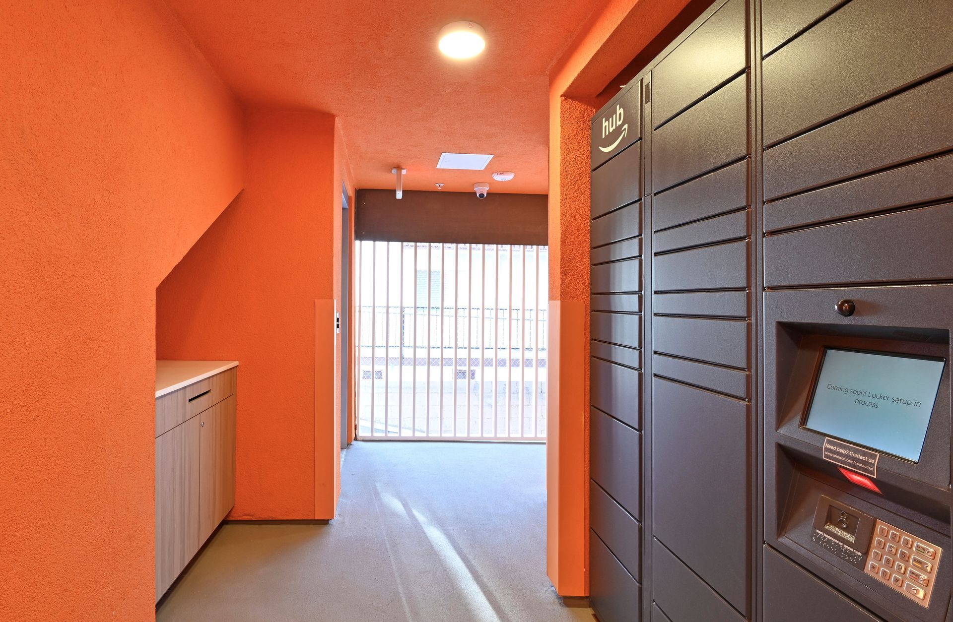 Orange hallway with package lockers, a door, and a light.