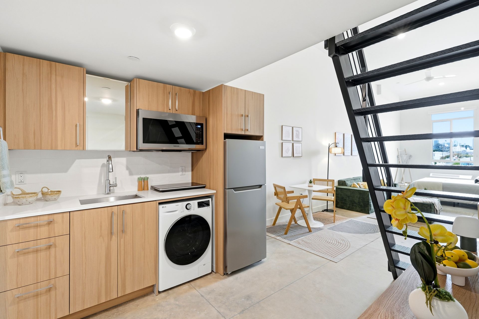 Modern kitchen with wood cabinets, stainless appliances, and a small dining area by a window.