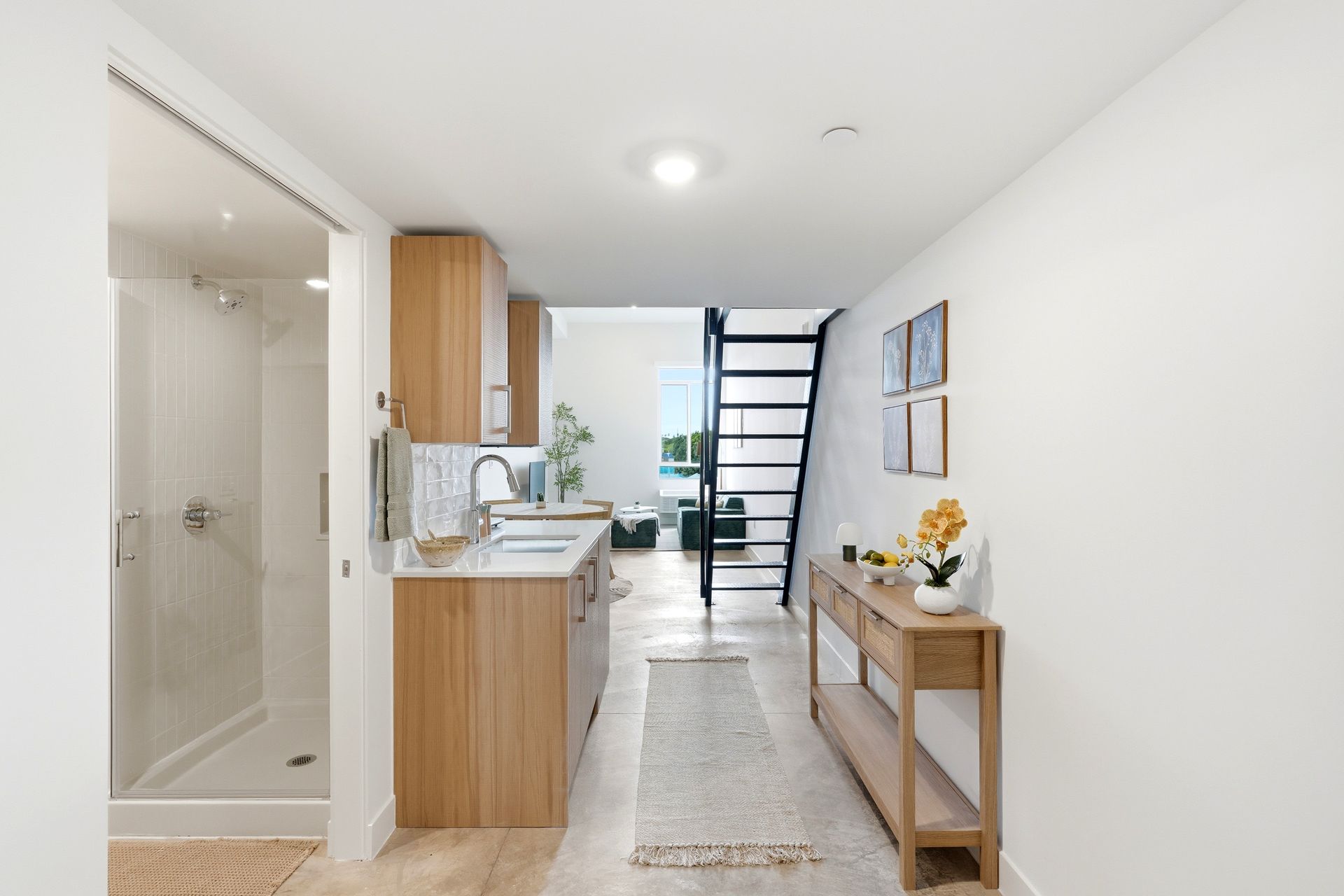 Bright hallway with kitchen, bathroom, staircase, and wooden console table in a modern home