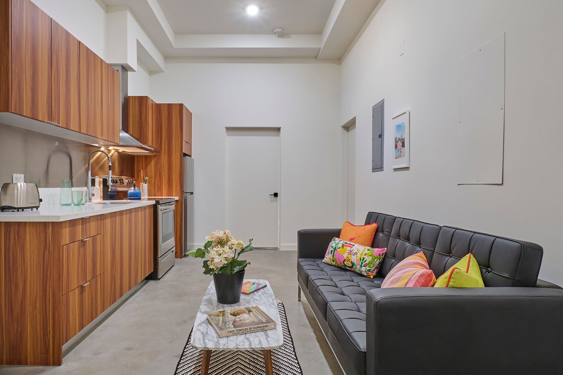A living room with a couch , coffee table , and kitchen.