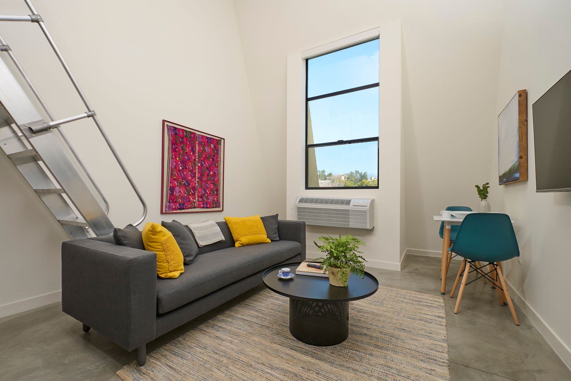 A living room with a couch , table , chairs and stairs.