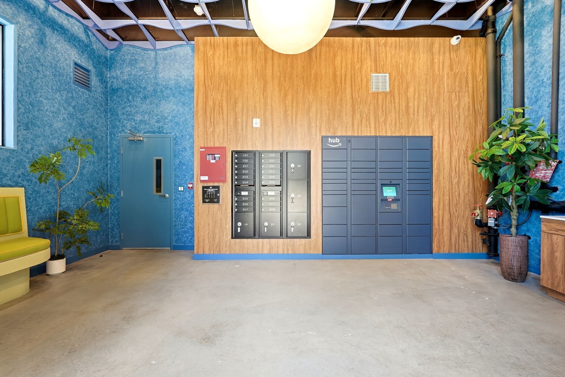 Modern lobby with mailboxes, blue and wood-paneled walls, and potted plants