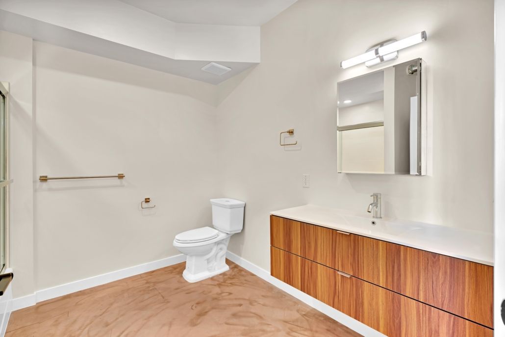 A bathroom with a toilet , sink and mirror.