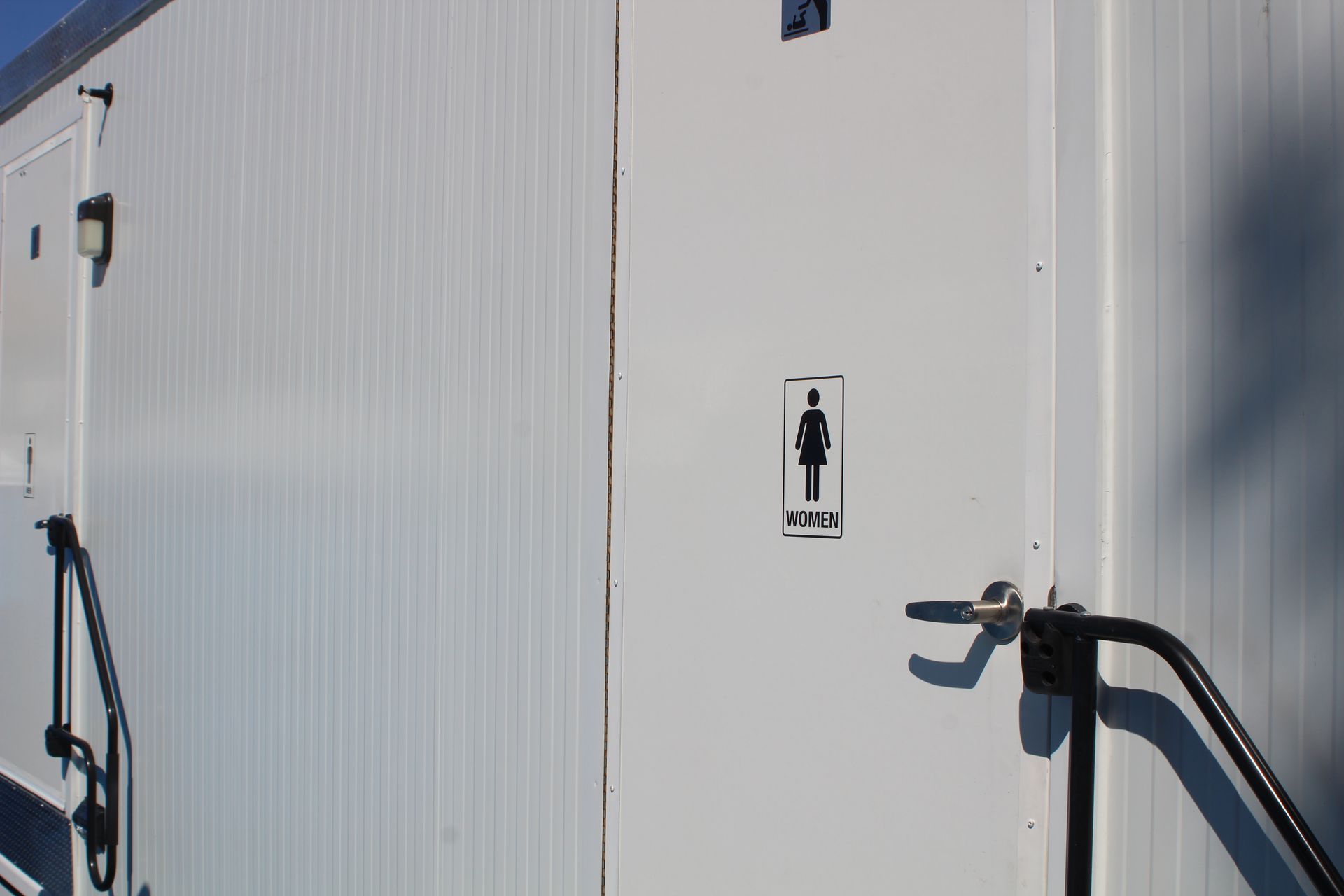 A white building with a sign on the side that says female restroom.