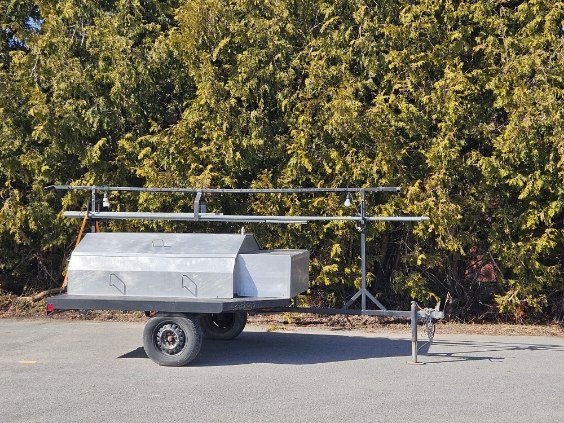 A trailer is parked in a parking lot with trees in the background.