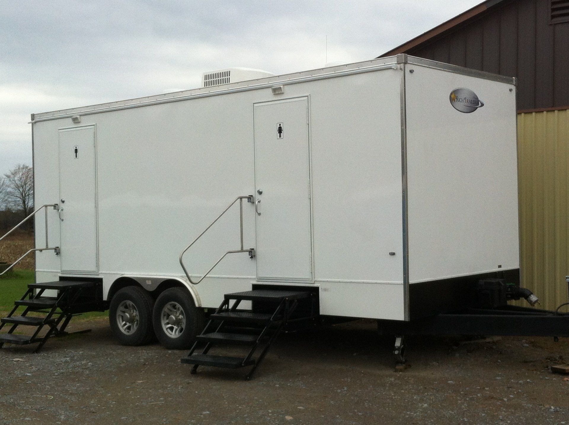 A white trailer with stairs is parked in front of a building