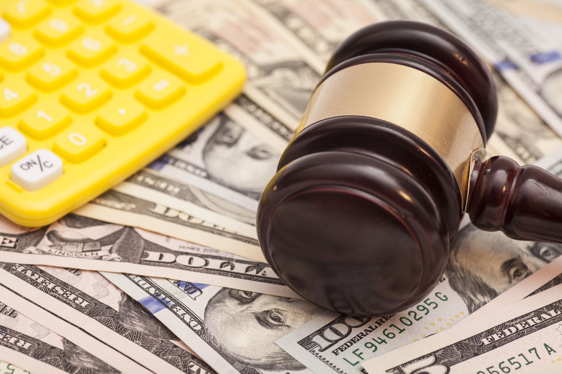 A judge 's gavel is sitting on top of a pile of money next to a calculator.