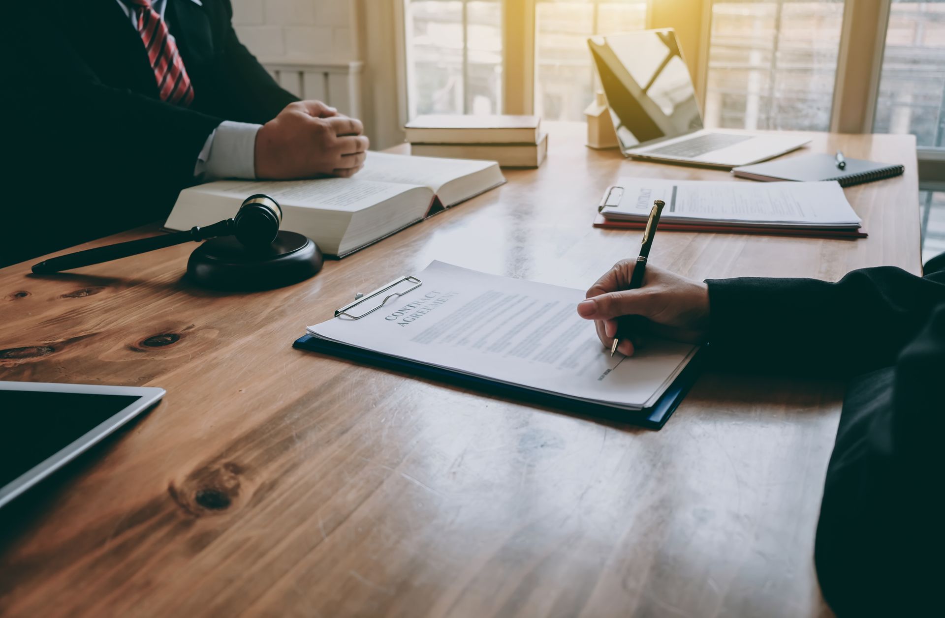 A man and woman are sitting at a wooden table signing a document.