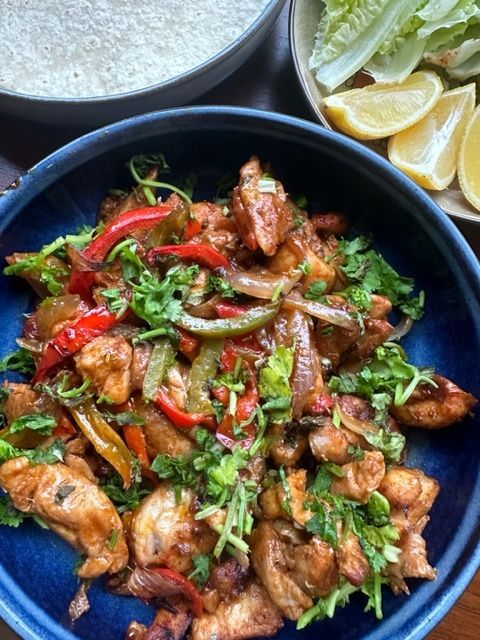 A blue bowl filled with chicken and vegetables on a table.