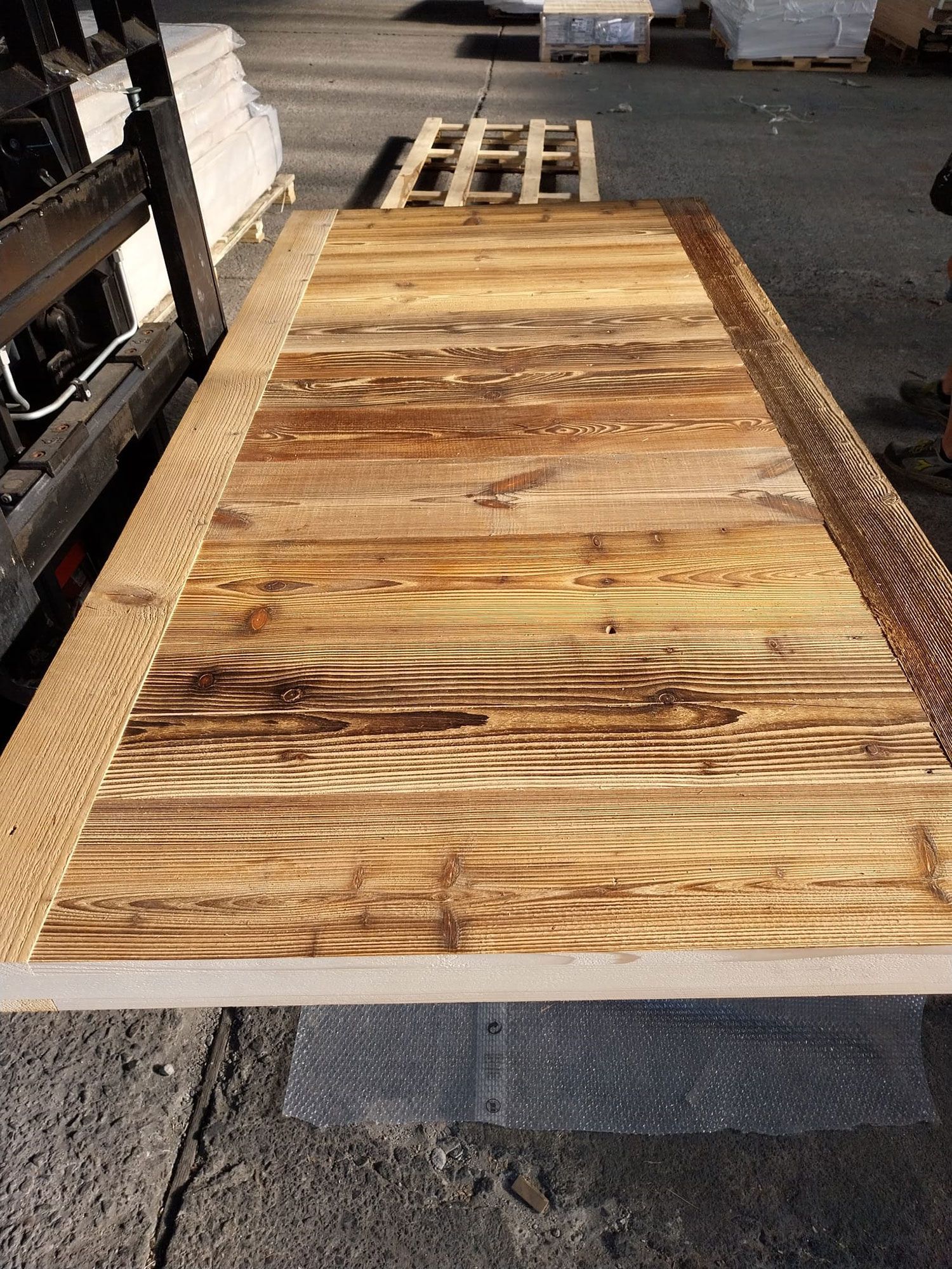 Grande tavolo rettangolare in legno con motivo a tavole, bordato da una cornice chiara e strutturata; per esterni.