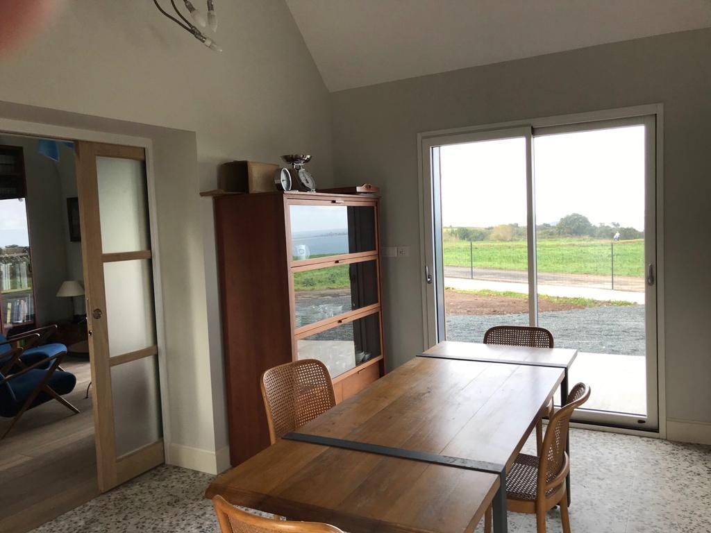 Una levigatrice a nastro largo con due teste di levigatura lavora una lunga asse di legno in un'officina.