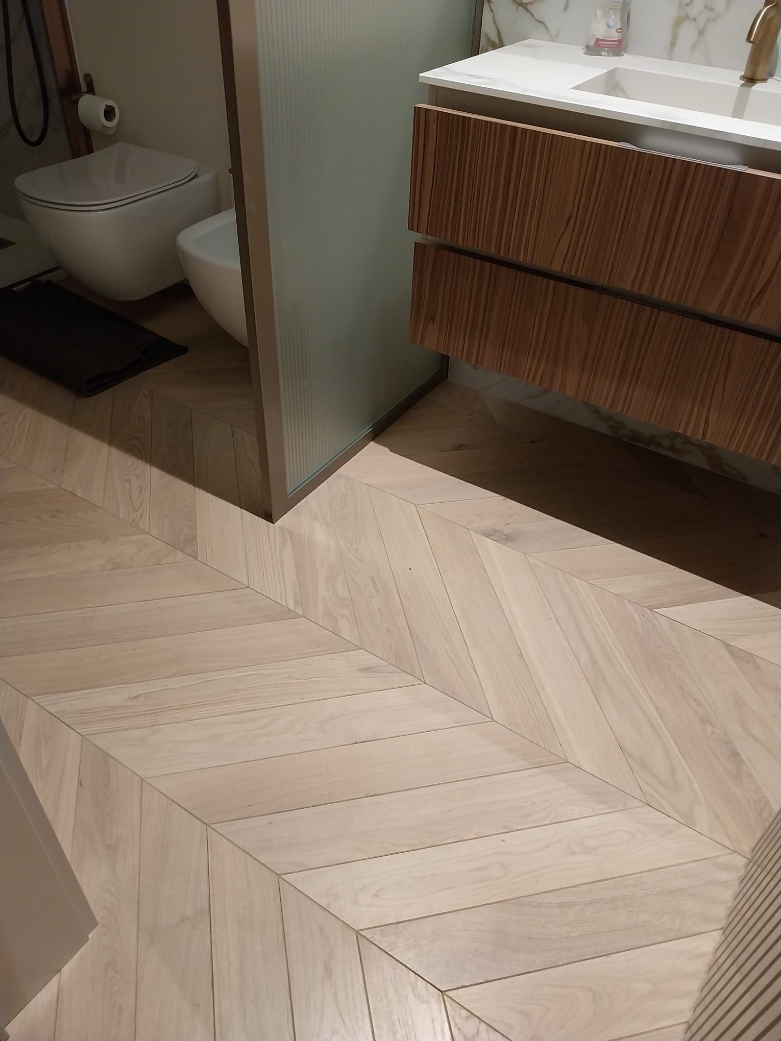 Pavimento in legno a spina di pesce in un bagno moderno.