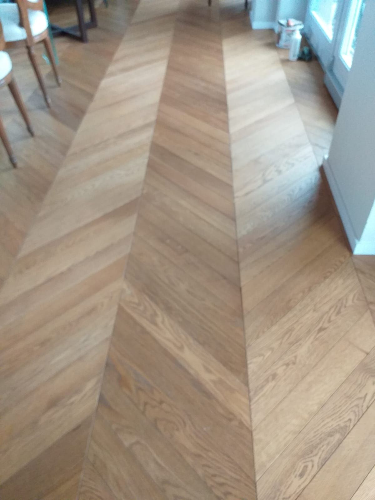 Pavimento in legno marrone chiaro con motivo a zig-zag in una stanza.