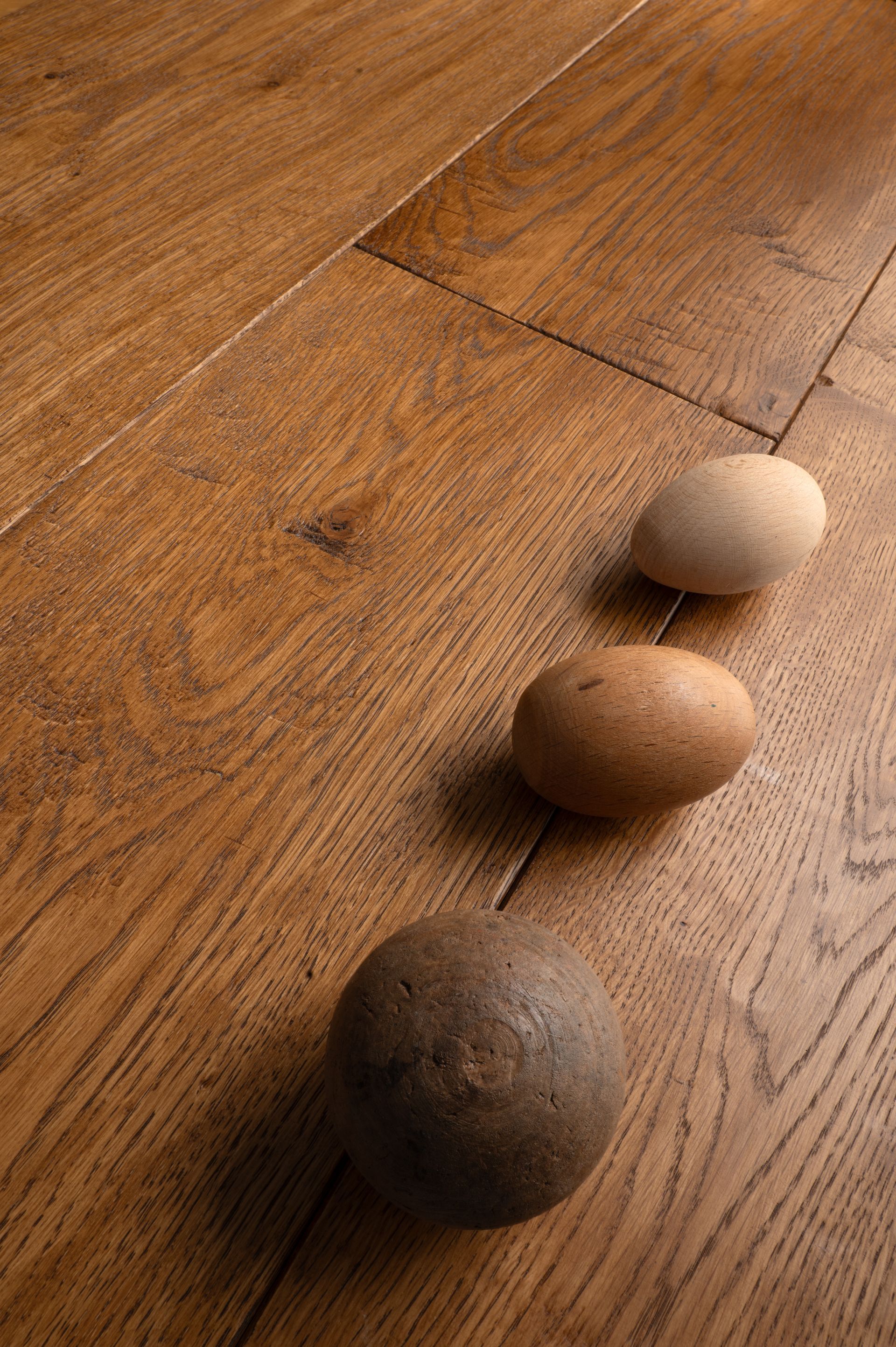 Tre pietre lisce in una sfumatura di colori su assi del pavimento in legno.