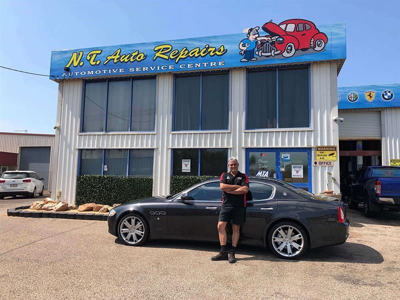 Three Men Are Posing for a Picture in Front of a Red and White Car — NT Auto Repairs in Winnellie, NT