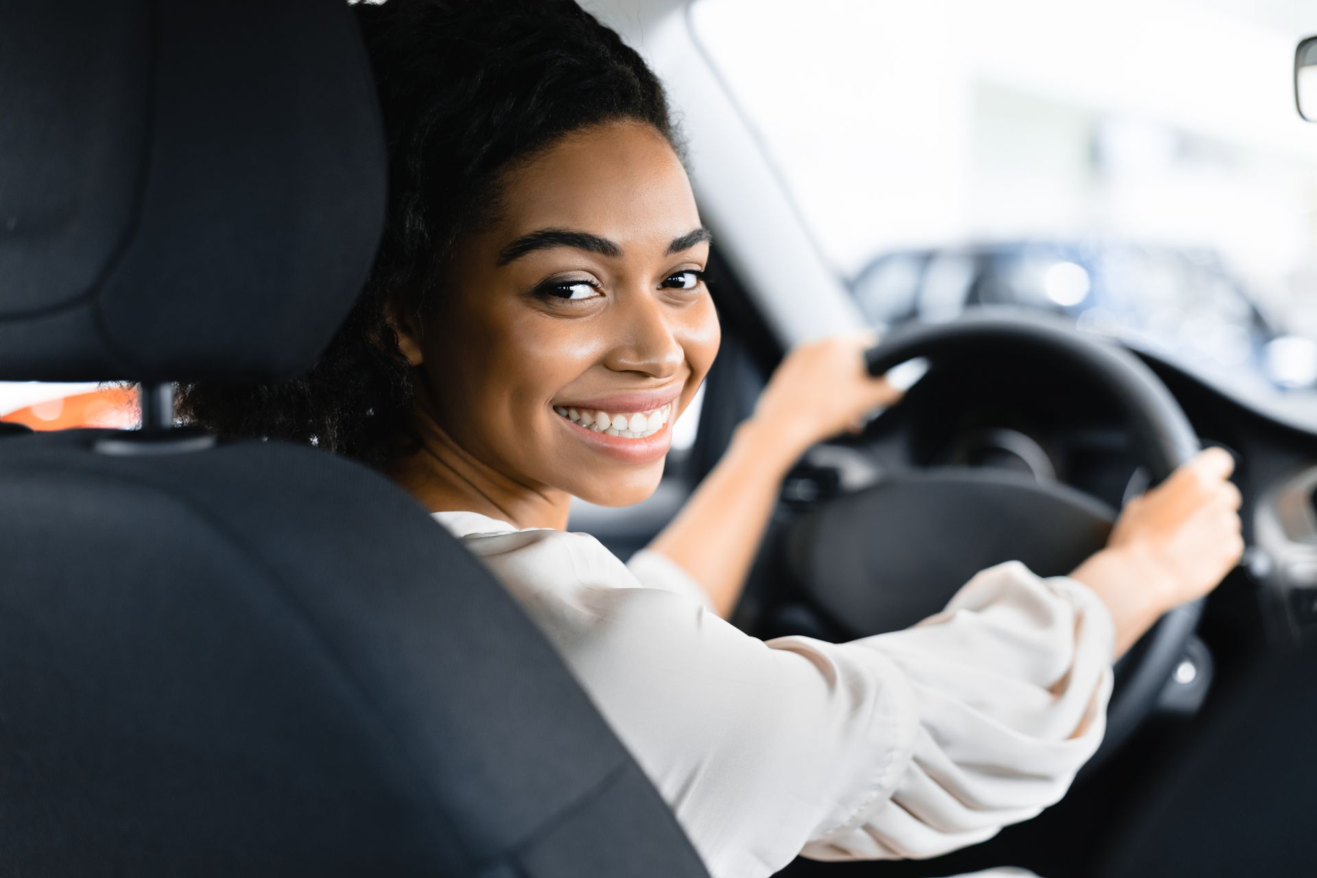 Driver holding the steering wheel while seated in a vehicle’s front seat during a daytime ride.