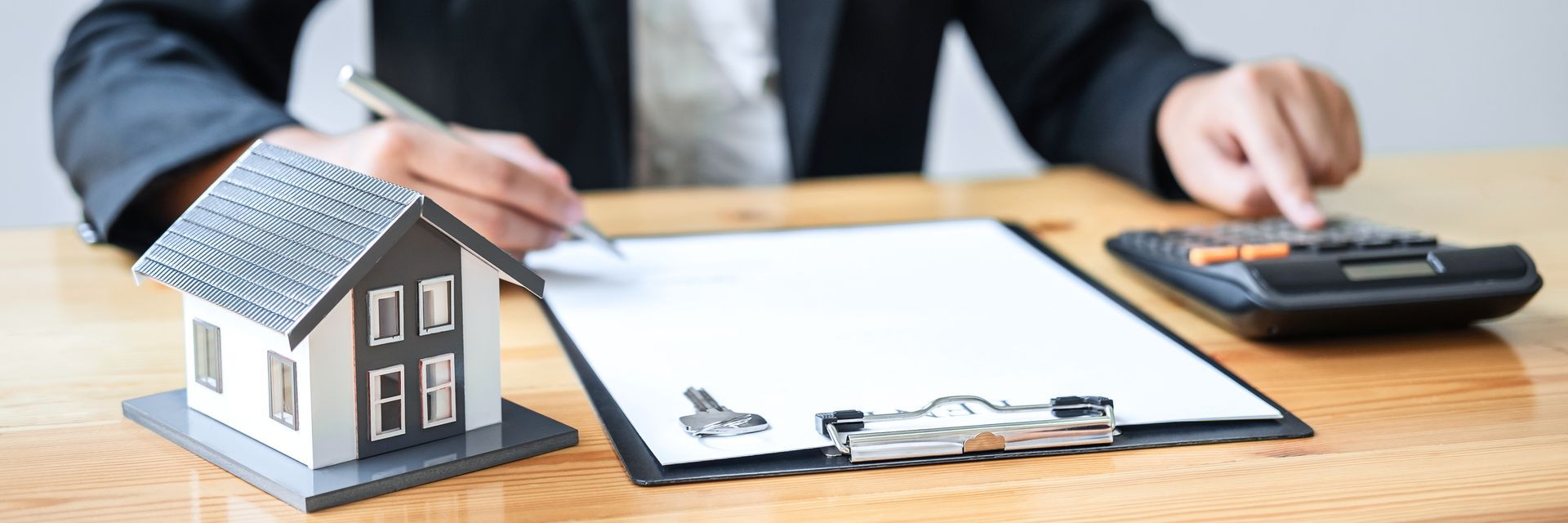 Close up of agent highlighting home insurance amid home designs and contract calculator. Close up of agent highlighting home insurance amid home designs and contract calculator.