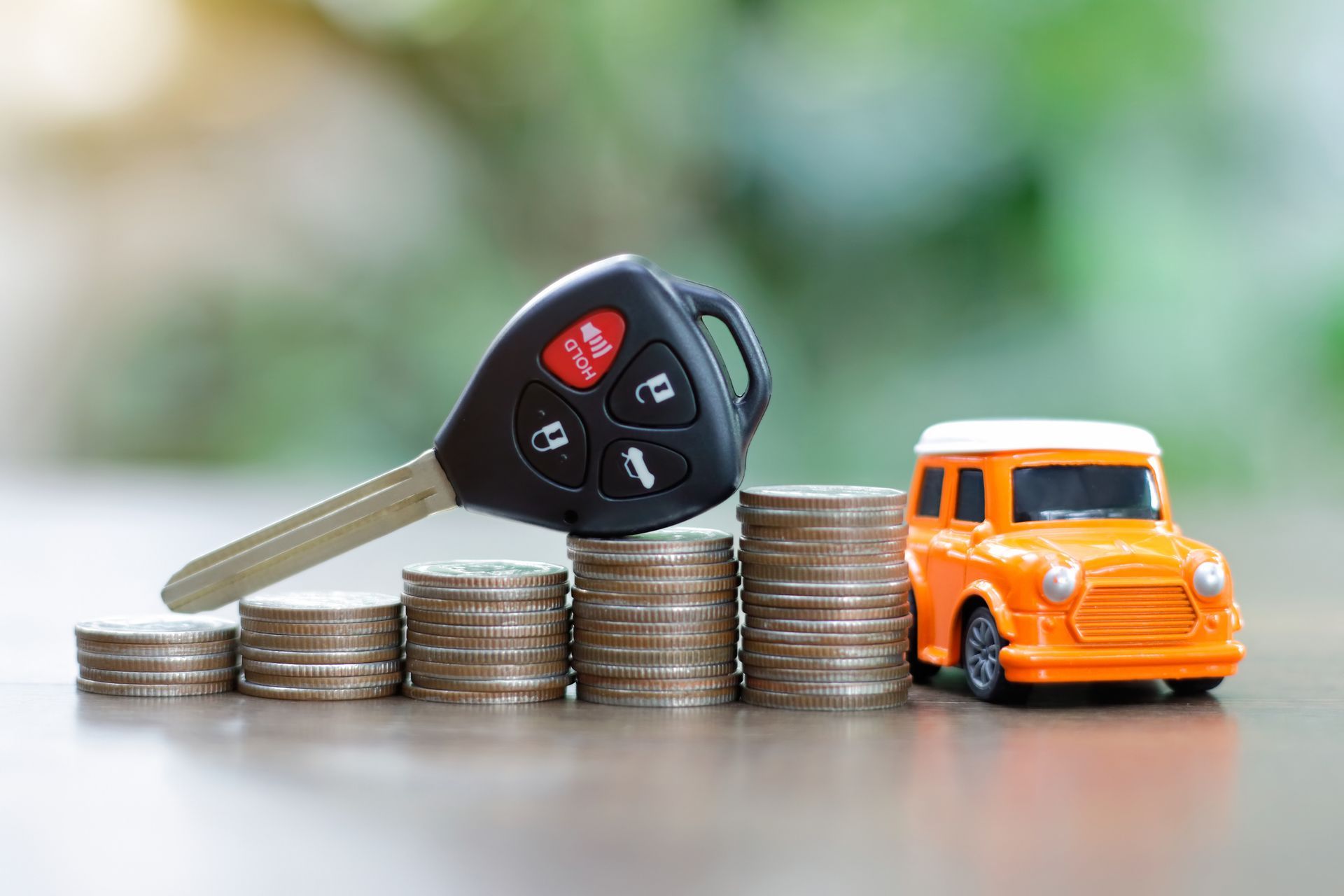 Car keys on a pile of coins and a model car. Car keys on a pile of coins and a model car.