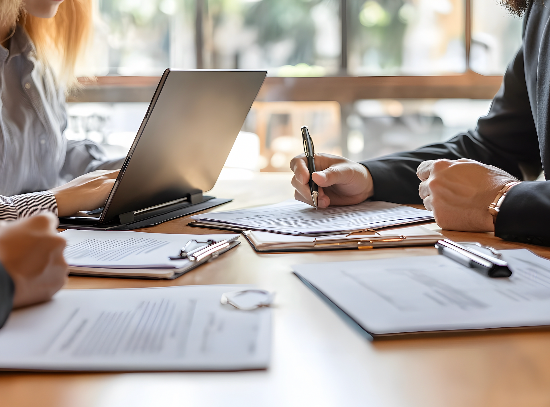 A group of people are sitting at a table with papers and a laptop.