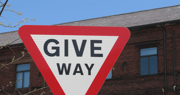 A Give Way Sign In Front Of A Brick Building — PTS Traffic Management in Smithfield, QLD