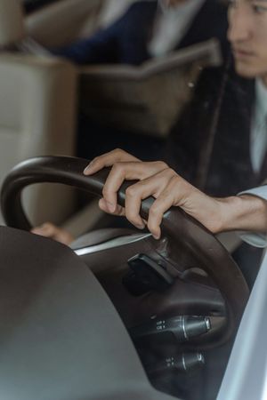 A man is driving a car with his hands on the steering wheel.