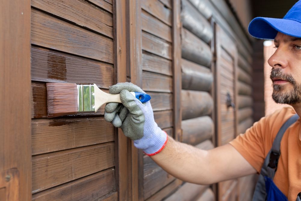 A man is painting a wooden wall with a brush.