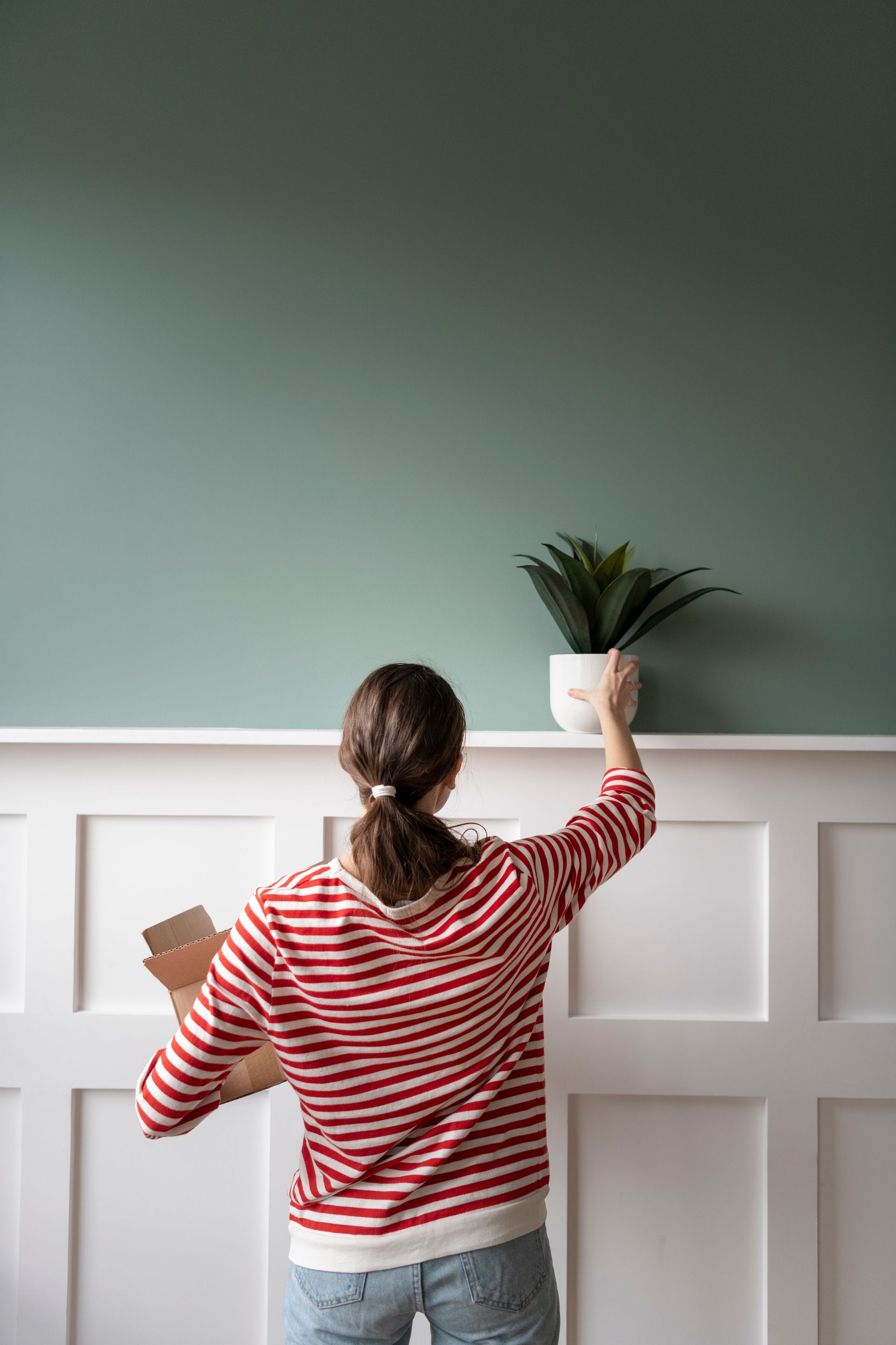 woman placing a potted plant in a room