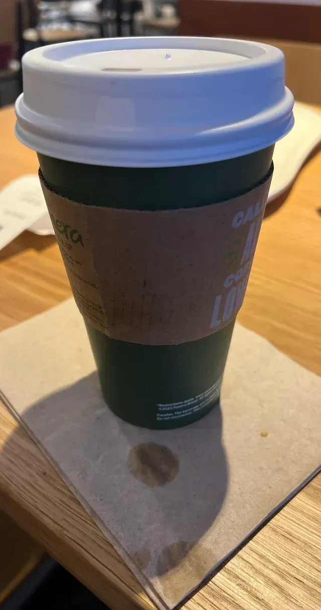 A cup of coffee is sitting on a napkin on a wooden table.