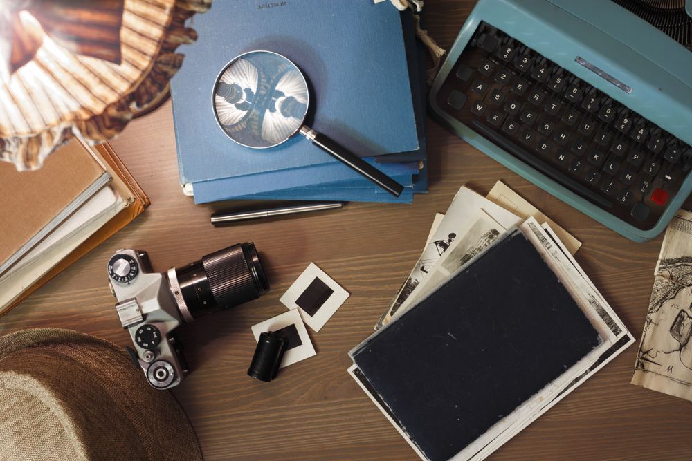 a desk with a typewriter , camera , magnifying glass , and other items .