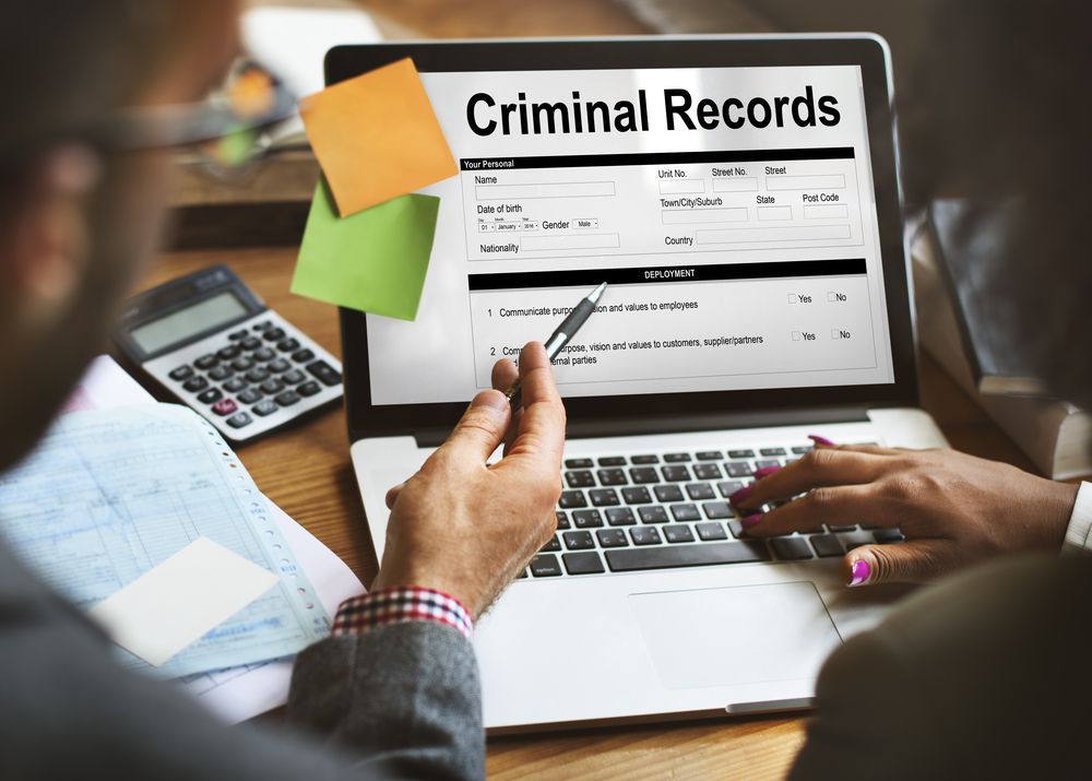 a man and a woman are looking at criminal records on a laptop .