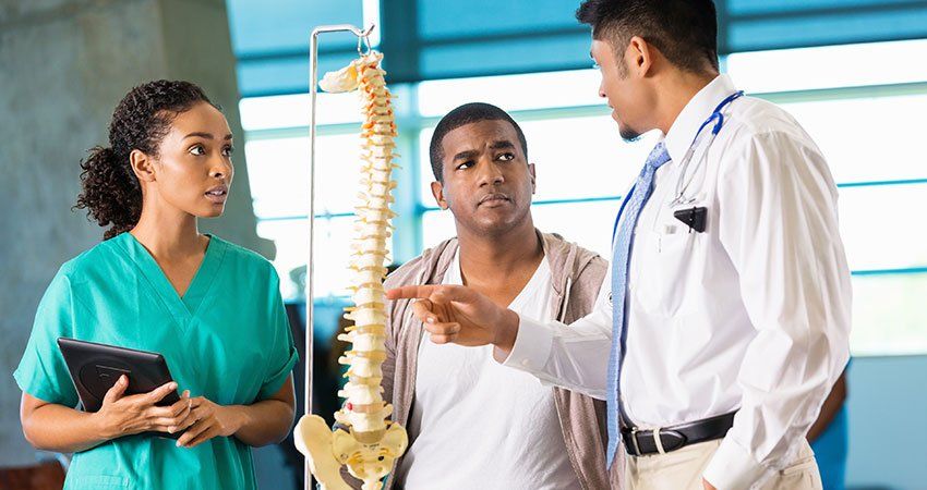 Doctor and nurse showing patient a model spine