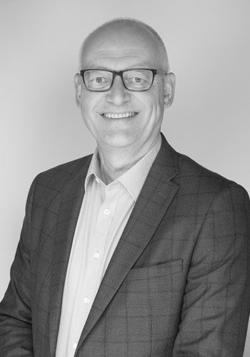 dale at sabre insurance in a suit and glasses is smiling in a black and white photo .