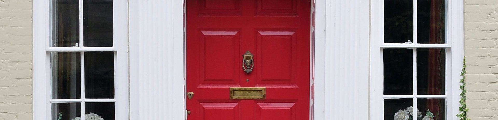 a red door with a white frame is on a white house .