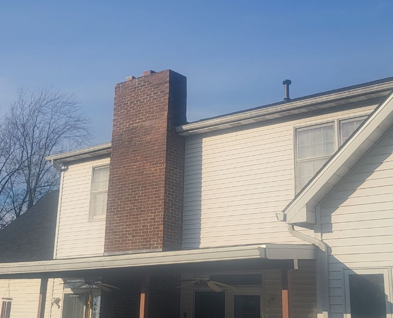 A white house with a brick chimney on the roof