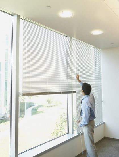 Businessman adjusting window blinds