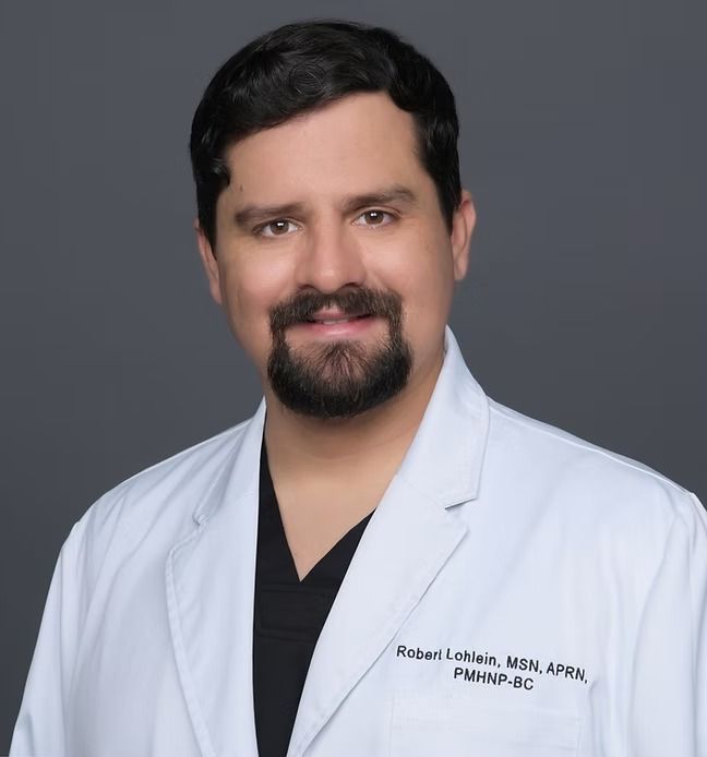 A man with a beard is wearing a white lab coat