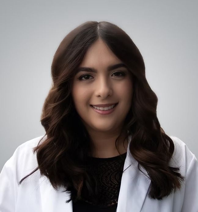 A woman in a white lab coat is smiling for the camera