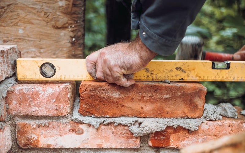 A man is using a level to check the level of a brick wall.