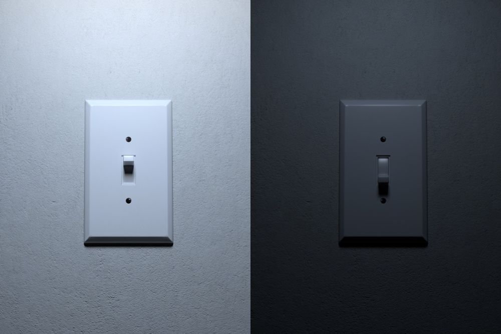 A light switch on a textured wall is shown on, illuminating the left, and off, darkening the right.