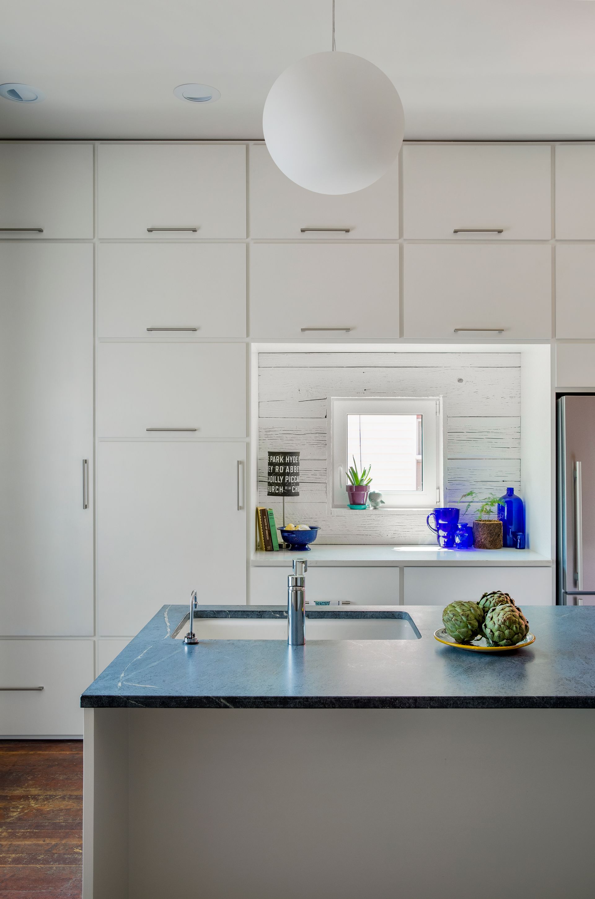 Rustic modern cabin living room design with stone fireplace, leather lounge chairs, wood ceiling, and forest views