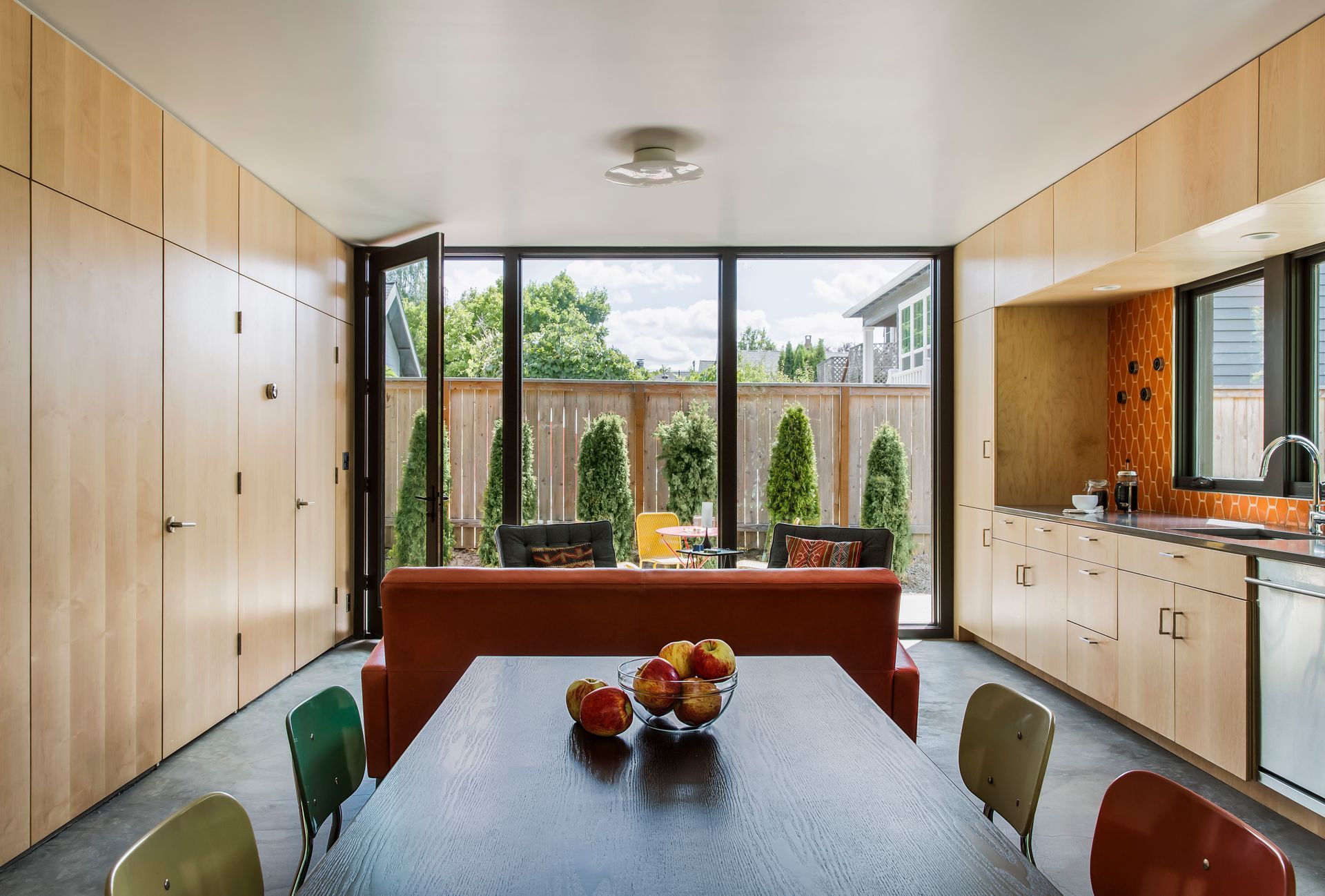modern kitchen with orange tile backsplash and open kitchen living space with red sofa and indoor outdoor connection Portland Oregon