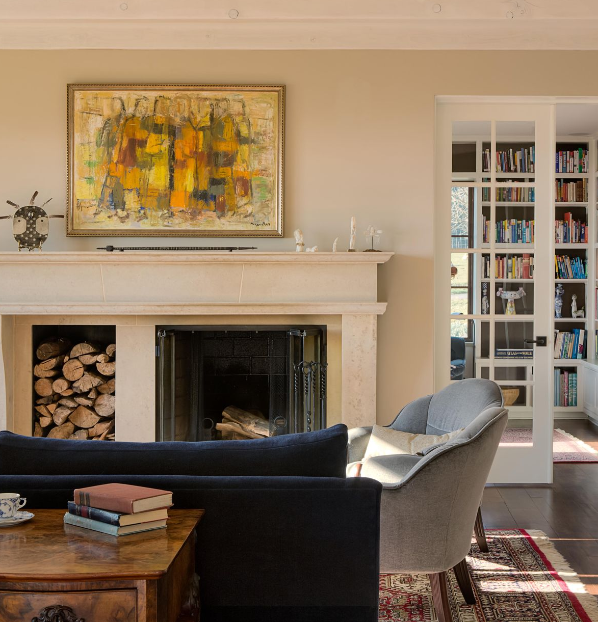 Living room with fireplace, layered textures, vintage furnishings and natural light in a refined Portland home